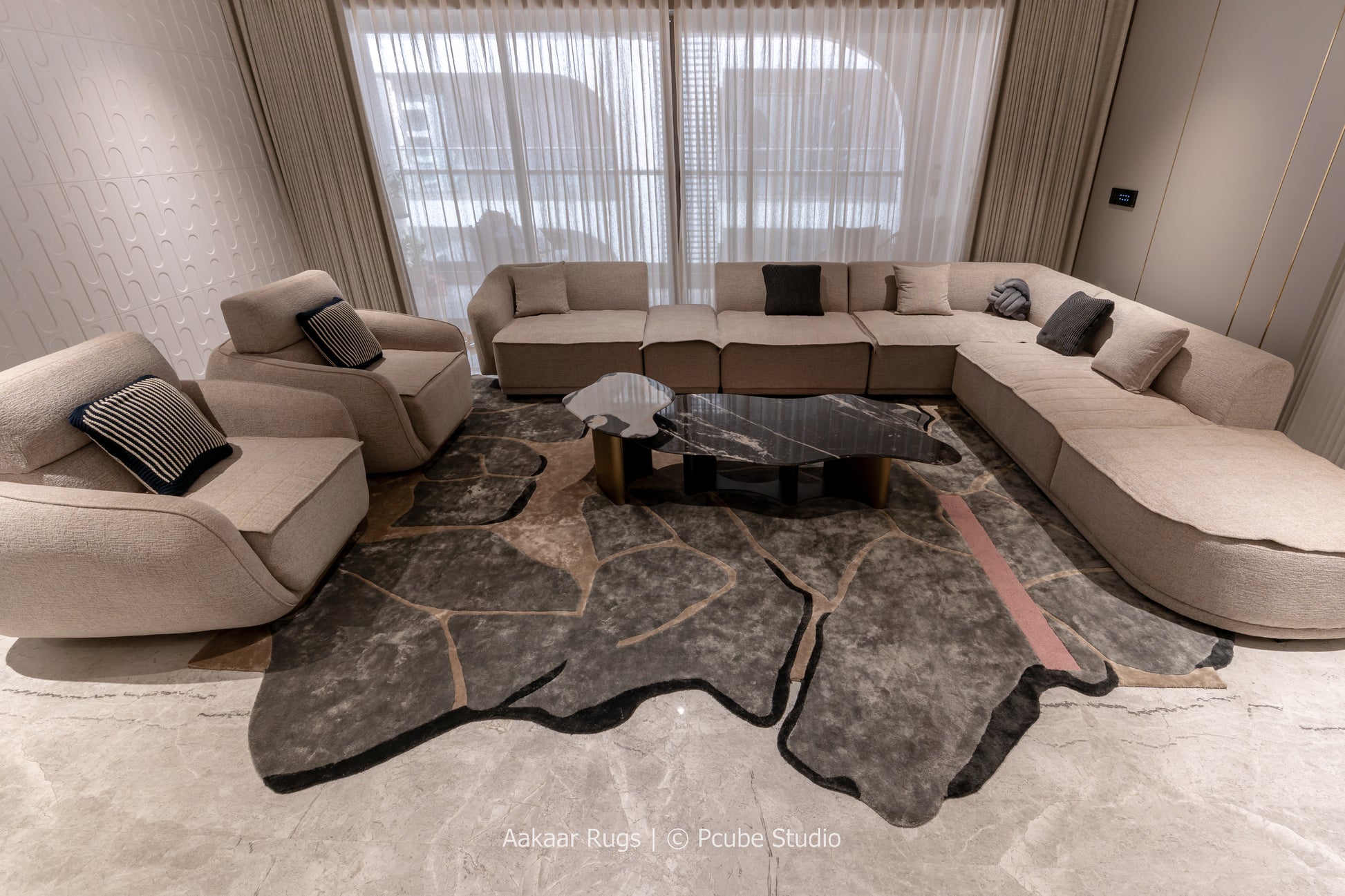 Modern living room with beige sectional sofa and dark area rug.